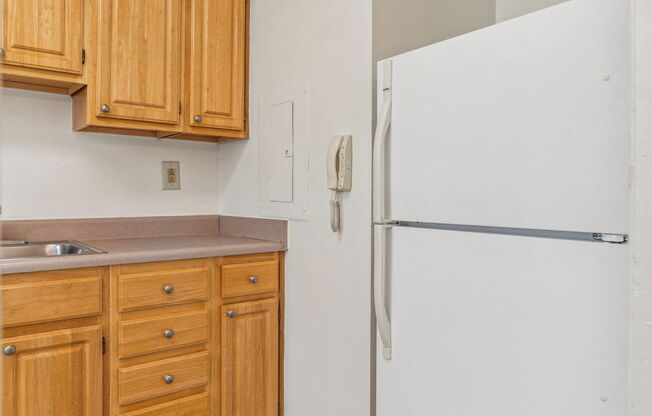 a kitchen with a white refrigerator and wooden cabinets