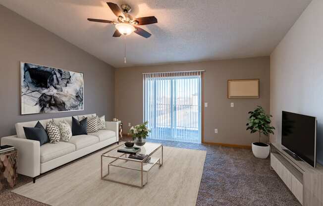 an open living room with a couch and a tv. Fargo, ND Sunwood Apartments