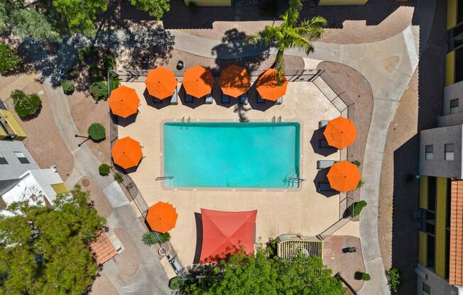 arial view of a swimming pool with orange umbrellas and a red tent