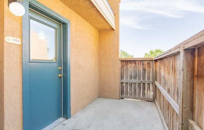 the balcony has a blue door and a wooden fence