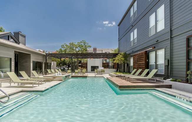 a pool with lounge chairs and a hot tub in front of a building