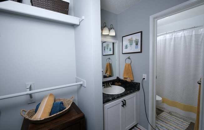 Fusion Fort Worth studio apartment bathroom with single sink and separate room for bathtub and toilet. Closet area next to sink with two curtain rods.