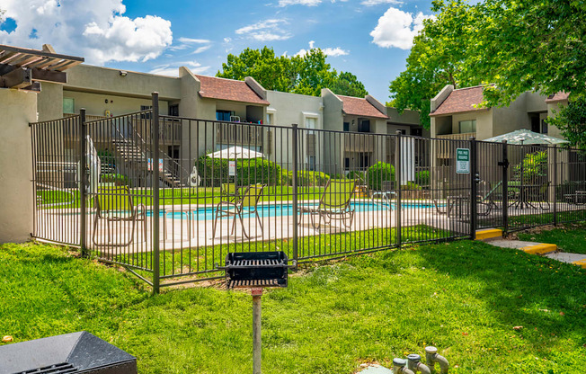 A black fence surrounds a pool and a building.