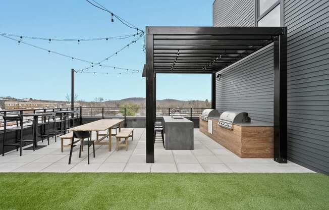 a rooftop patio with a barbecue grill and a table and chairs