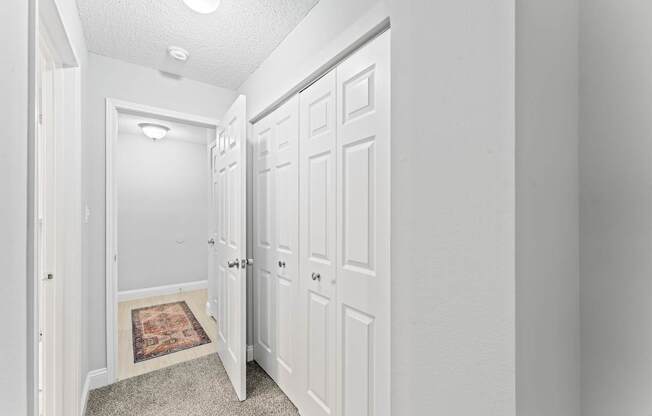 A hallway with white doors and a rug on the floor.