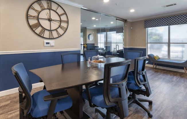 a conference room with a table and chairs and a clock on the wall