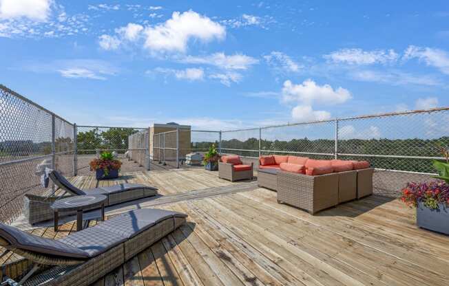 a deck with couches and chairs on top of a chain link fence