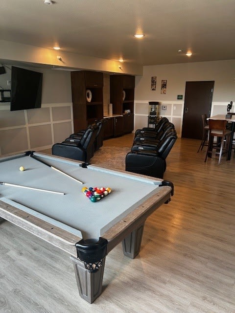 a living room with a pool table and chairs