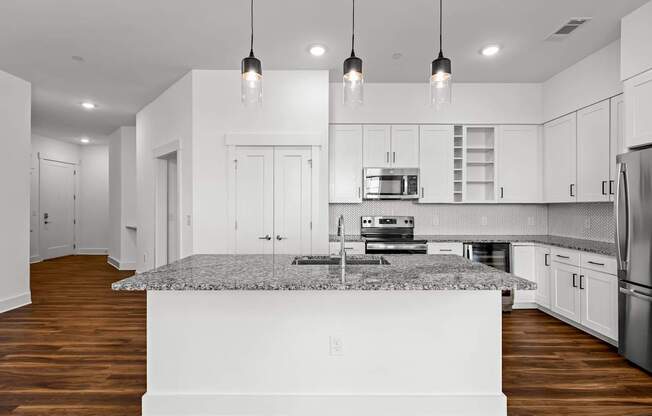 A modern kitchen with a granite countertop and stainless steel appliances.