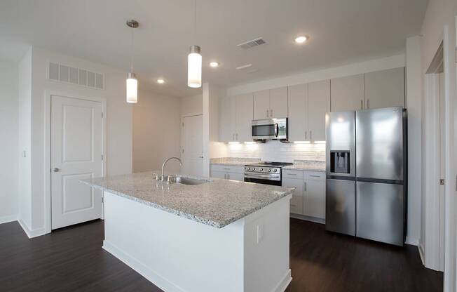 A kitchen with a granite countertop and stainless steel appliances.