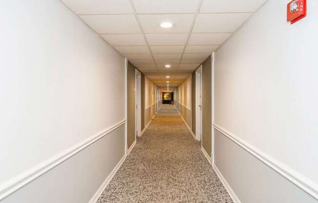 A long hallway with a carpeted floor and white walls.