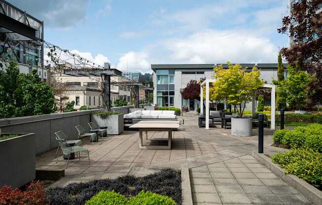 A patio with a table and chairs surrounded by greenery.