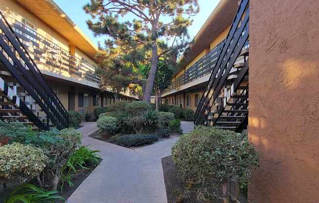 a courtyard between two buildings with plants and stairs