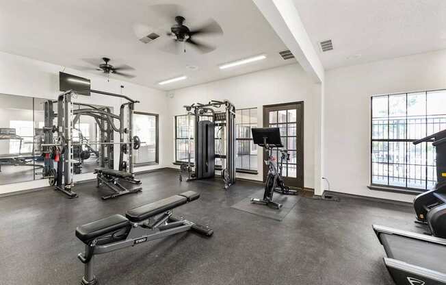 A spacious gym with a variety of equipment including treadmills, weights, and a bench press.