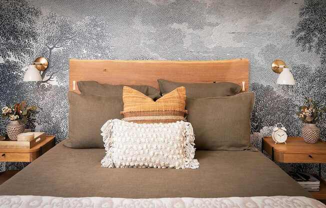 A bed with a wooden headboard and a grey wallpaper in the background.