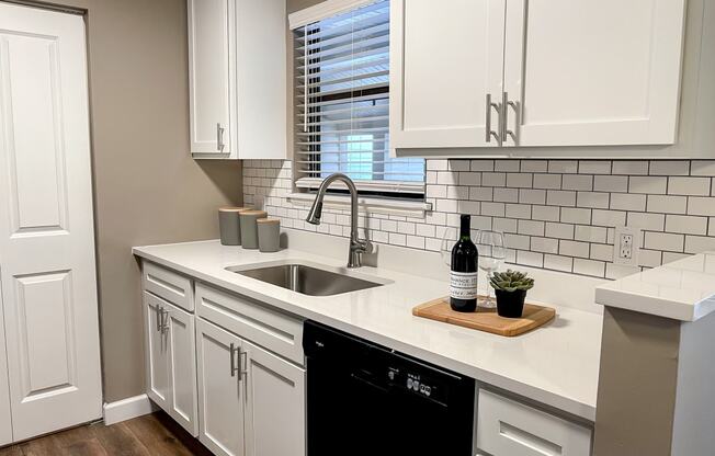 a kitchen with white cabinets and a sink and a window