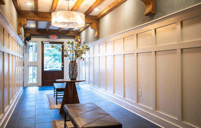 A long hallway with a bench and a vase on a table.