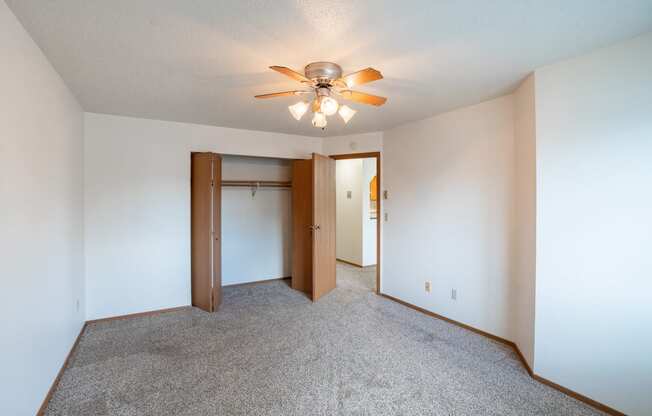 a bedroom with a closet and ceiling fan. Fargo, ND Westview Towers Apartments | Bedroom