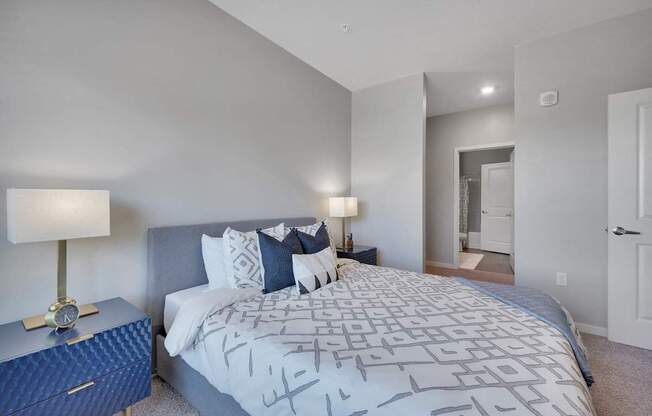 A bedroom with a large bed and a nightstand with a lamp.
