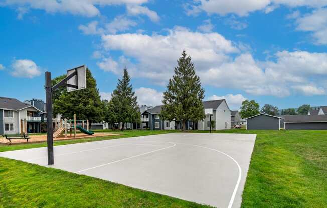 a basketball court in a park with houses in the background