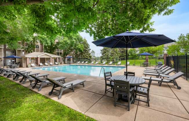 a swimming pool with patio furniture and umbrellas