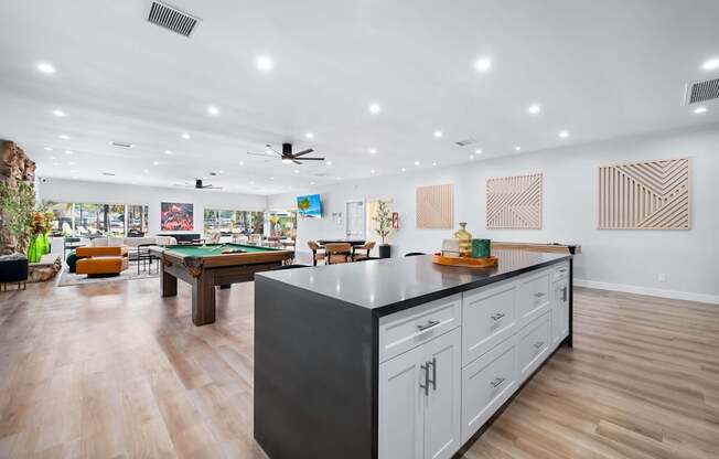 A modern kitchen with a pool table in the middle.