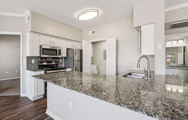 A kitchen with granite countertops and white cabinets.