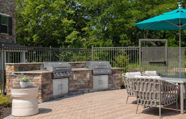 A patio with a table, chairs, and a grill.