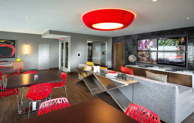 A modern living room with a grey couch and red chairs.