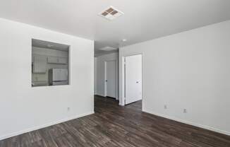 a living room with white walls and wood flooring and a large mirror