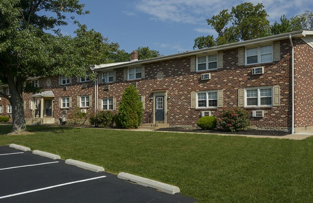 Exterior view of The Wellington complex with off-street parking spaces in front at Hatboro, PA apartment rentals