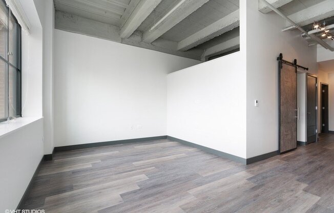 an empty room with white walls and wood floors