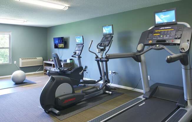 a gym with exercise equipment and televisions on the wall