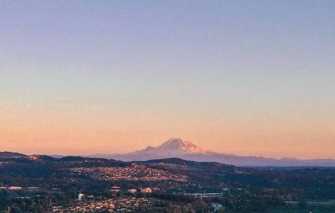 A cityscape with a mountain in the background and a crescent moon in the sky.