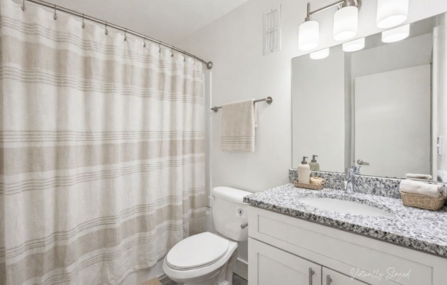 A bathroom with a toilet, sink, and shower curtain.