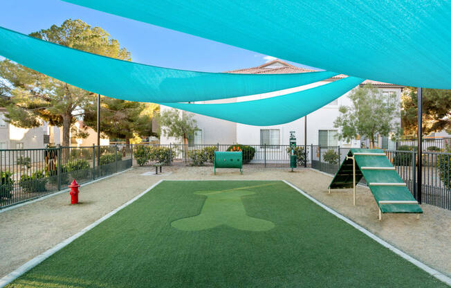 a green astroturf baseball field with a blue awning overhead