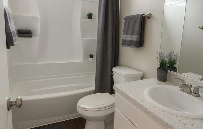 A white bathroom with a toilet, sink, and bathtub.