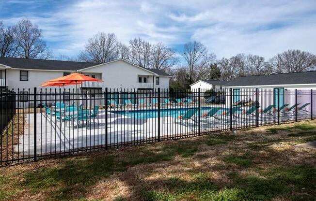 a pool with a fence in front of a house at Cleo Apartments, Athens, AL