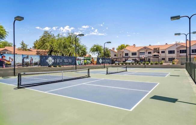 A tennis court with a banner that reads "HIDEAWAY" in the background.