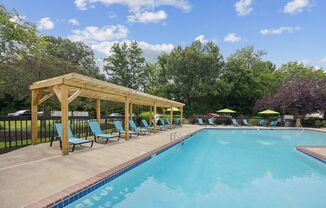 a swimming pool with blue chairs and a wooden pavilion next to it