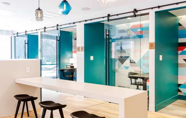 a conference room with a long white table and three black stools at One Ten Apartments, Jersey City , New Jersey