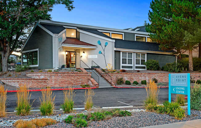 A modern house with a leasing center sign in front.