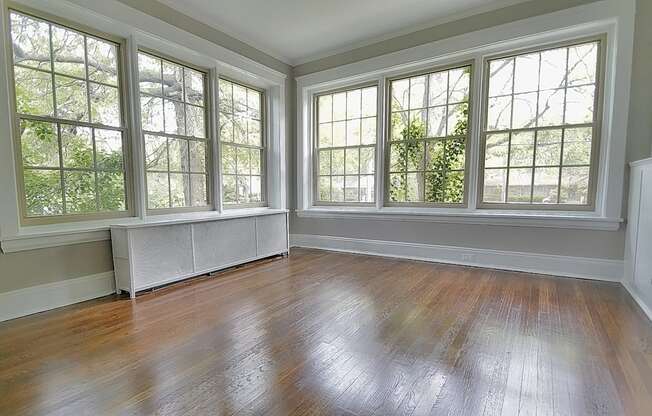 A room with a wooden floor and three windows.