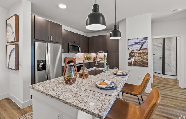 A modern kitchen with a granite countertop and stainless steel appliances.