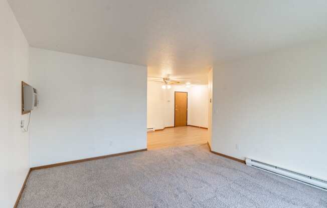 the living room and dining room of an apartment with white walls and wood flooring. Fargo, ND Flagstone Apartments