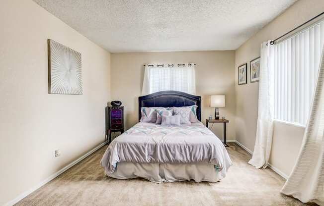 Carpeted bedroom with plush bedding and natural light in Aurora CO apartments for rent.