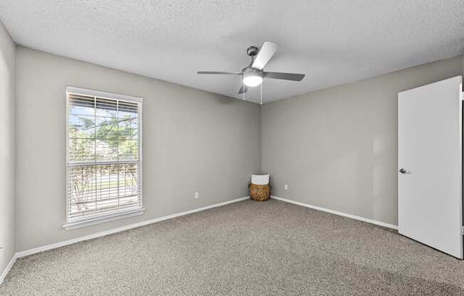 A room with a ceiling fan and a window with blinds.