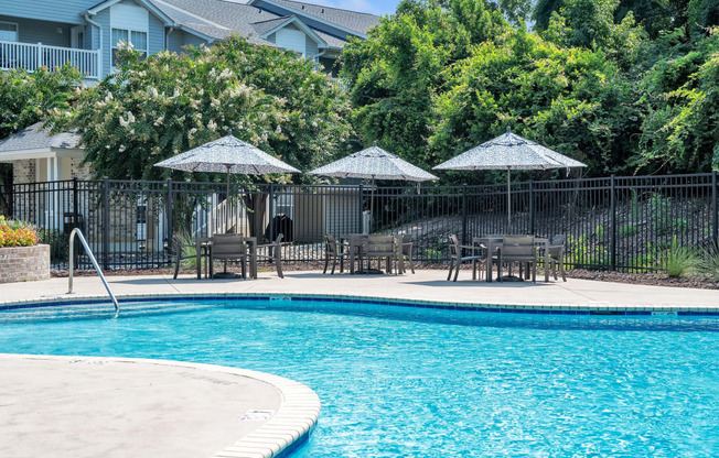 a swimming pool with patio furniture and umbrellas next to a resort style pool