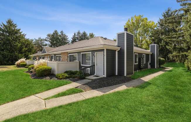 a small gray house with a sidewalk in front of it