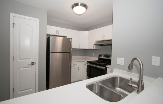 A kitchen with a sink, stove, and refrigerator. at Evergreen, Merrillville, 46410